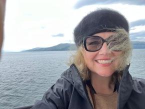 Laura Hope Gill on a boat with Scottish coastline in the background